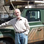 Photograph of Professor Herbert Lewis standing by truck in the field.